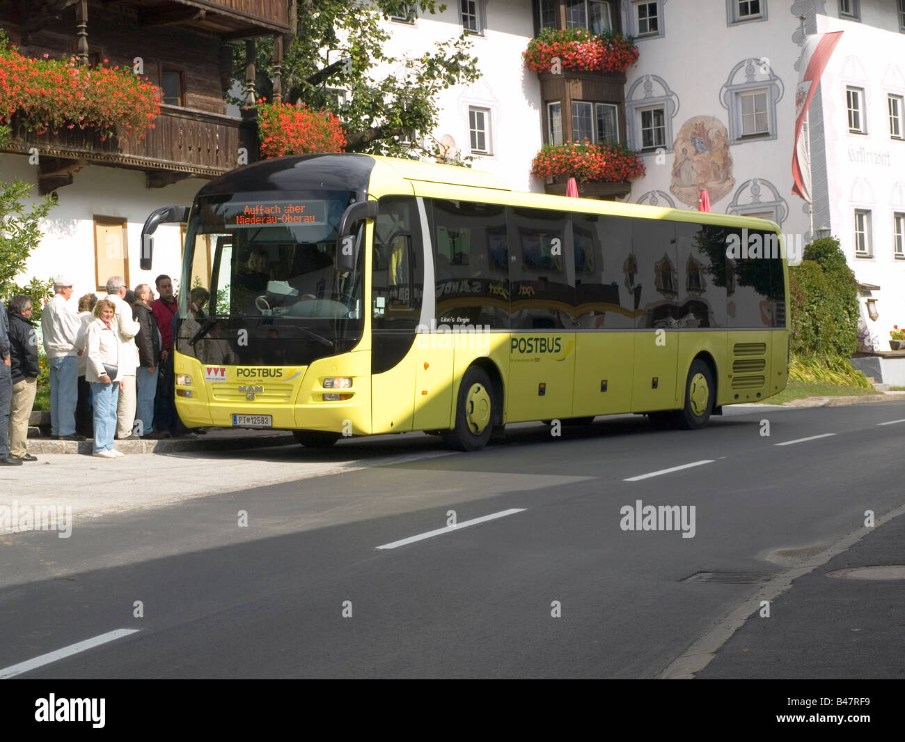 Tourists boarding a modern yellow postbus at Oberau Austria Stock Photo