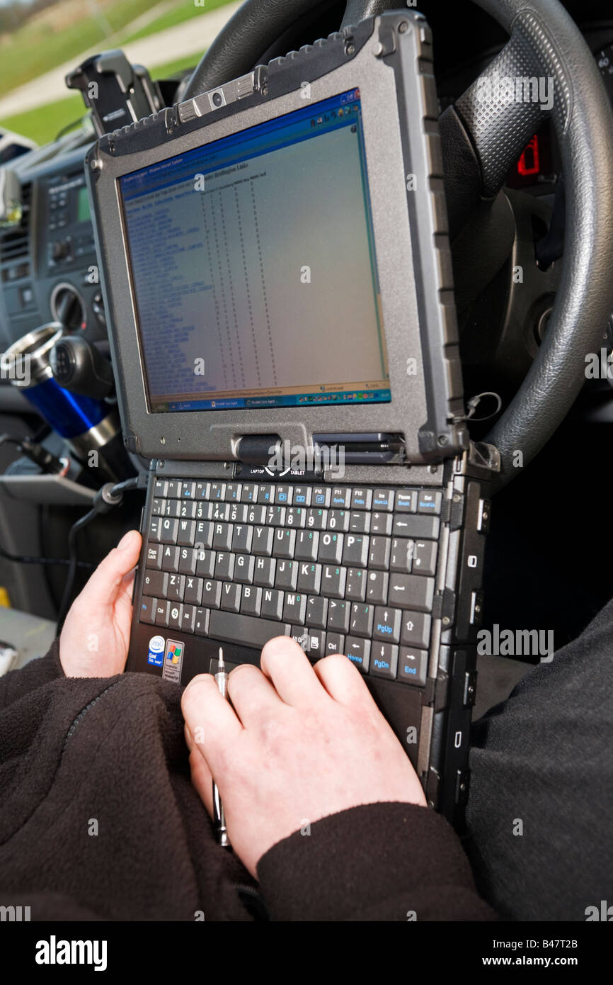 Mobile engineer using small rugged laptop computer in his van cabin to check his itinerary with his office to keep in touch Stock Photo