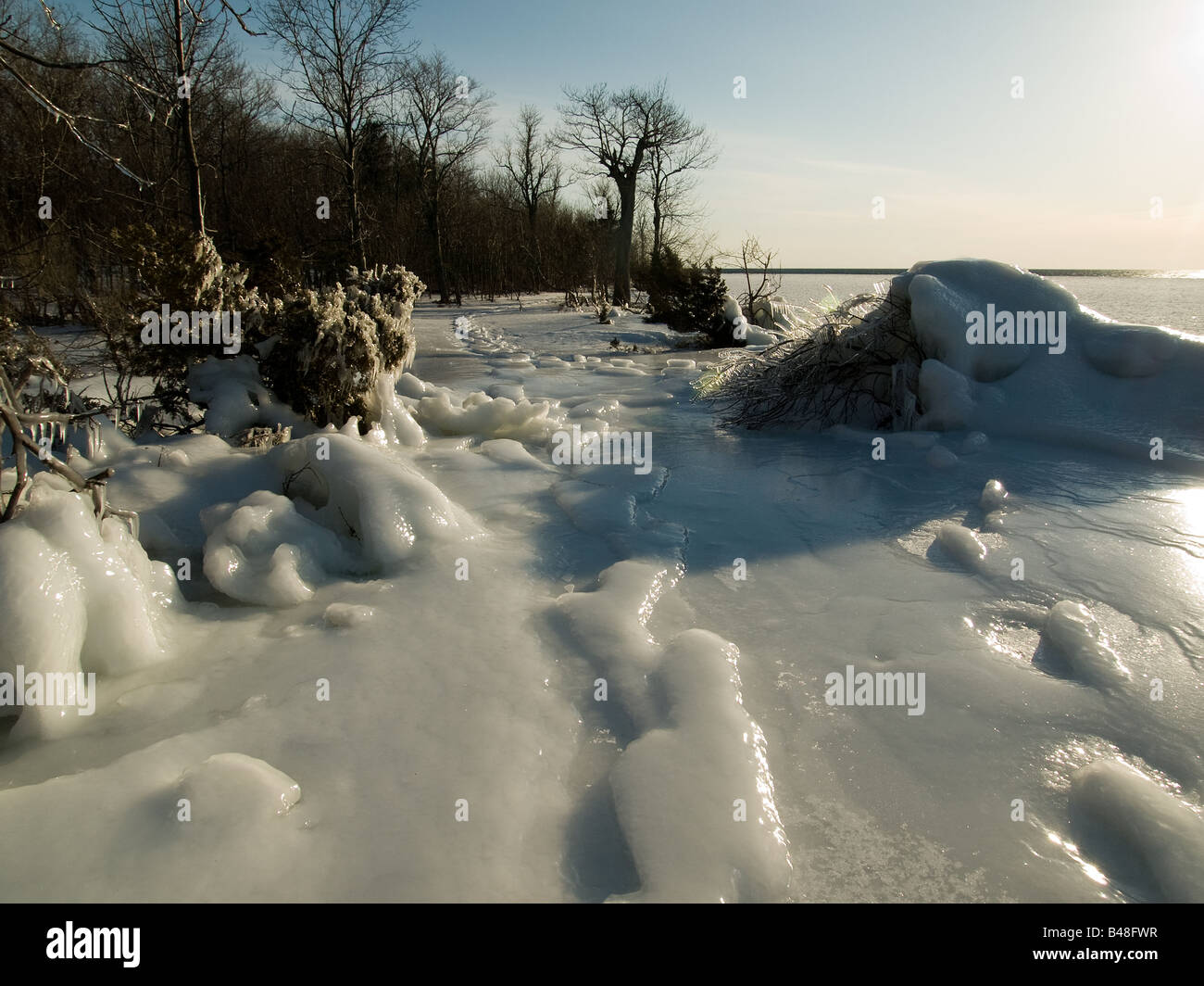 Ice covered snow on top of cliffs above Lake Ontario with snow shoe tracks leading the way down the path Stock Photo