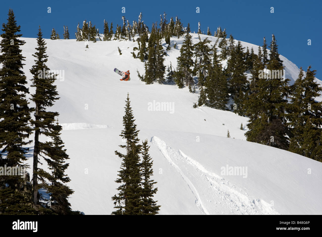 snowboarder jumping a huge jump in the back country of Whistler BC Stock Photo
