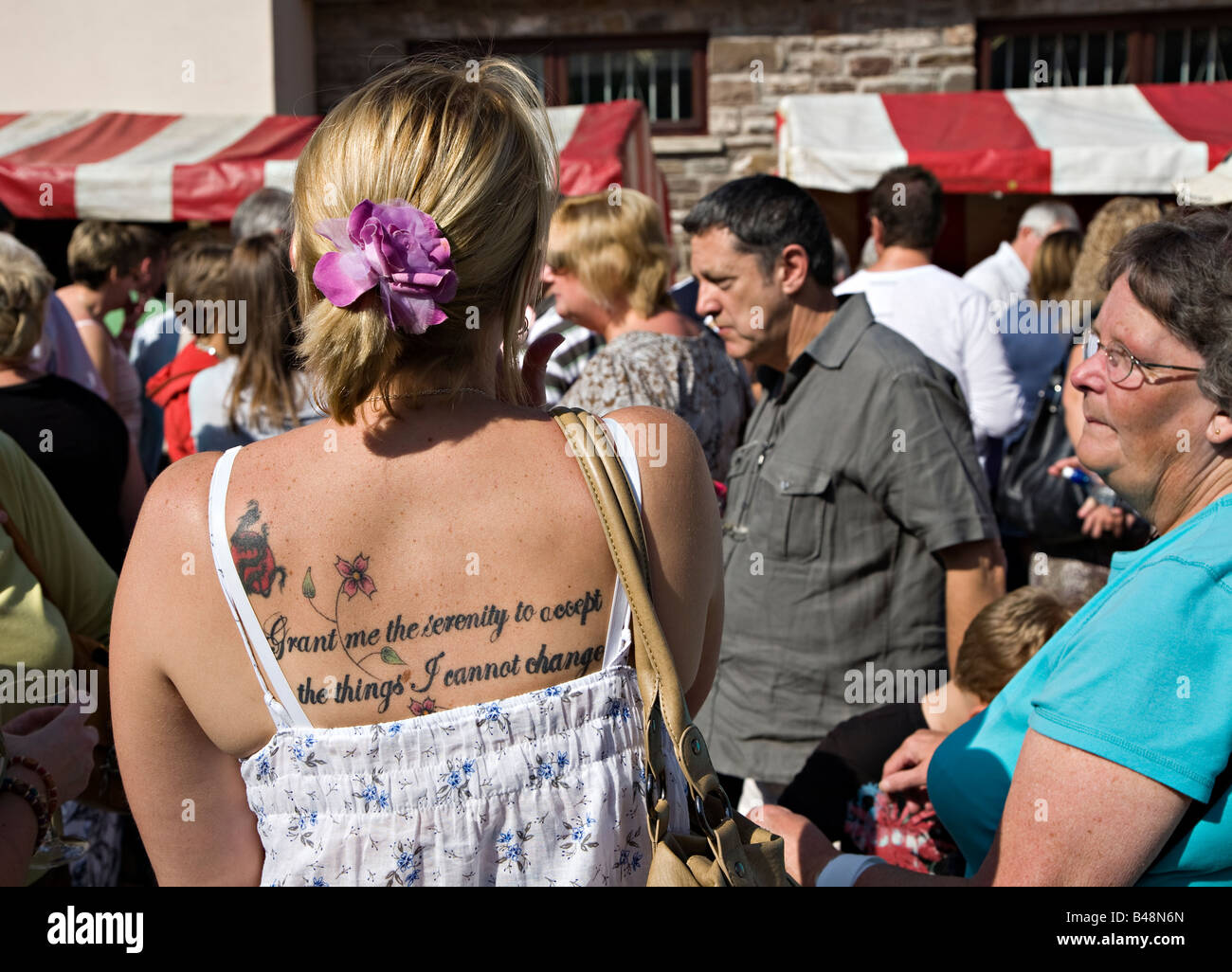Woman in crowd with tattoo on back reading Grant me the serenity to accept the things I cannot change Wales UK Stock Photo