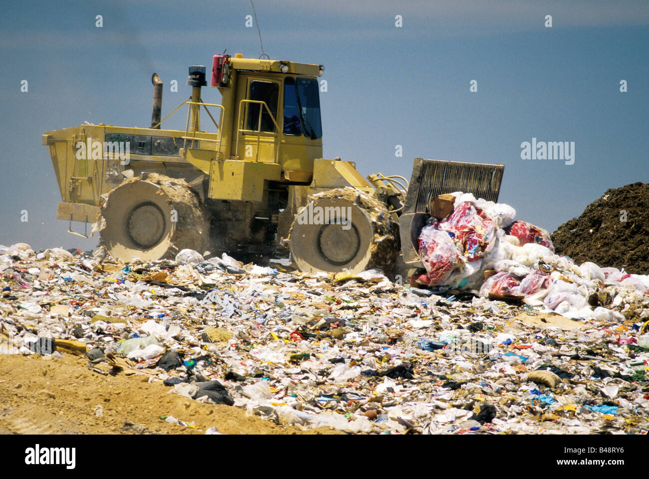Tractor compactor/dozer distributing trash at landfill. Stock Photo
