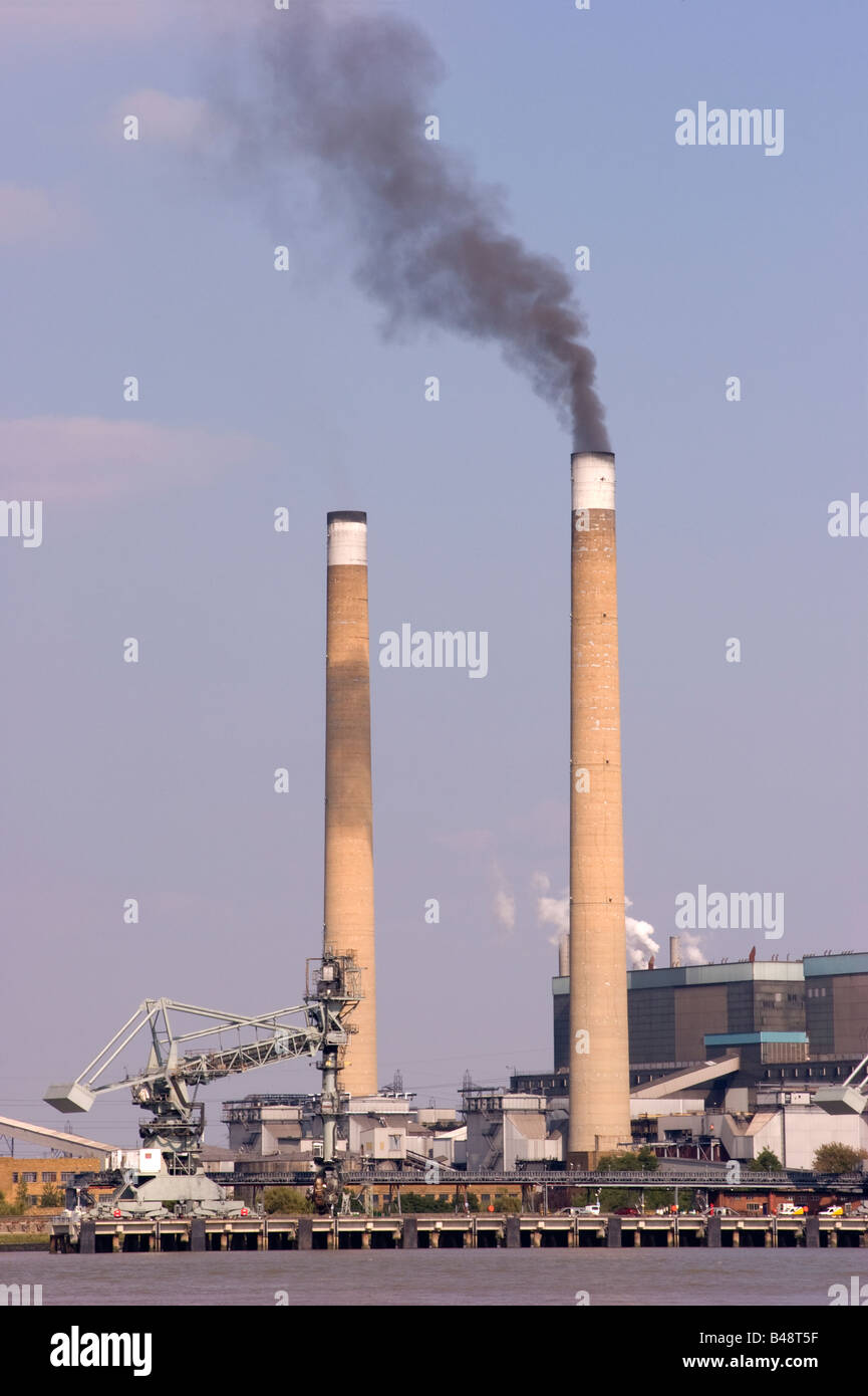 Black smoke being emitted from one of a pair of chimneys of the Barking coal fired power station on the banks of the River Thames in Essex. Stock Photo