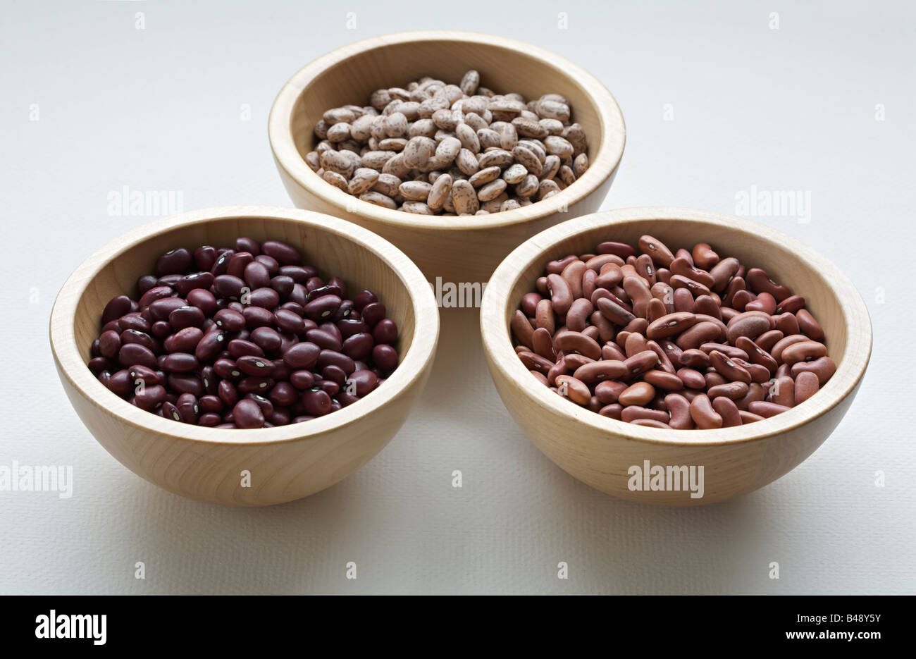 Assorted organic red beans, red kidney beans, and pinto beans in wooden bowls Stock Photo