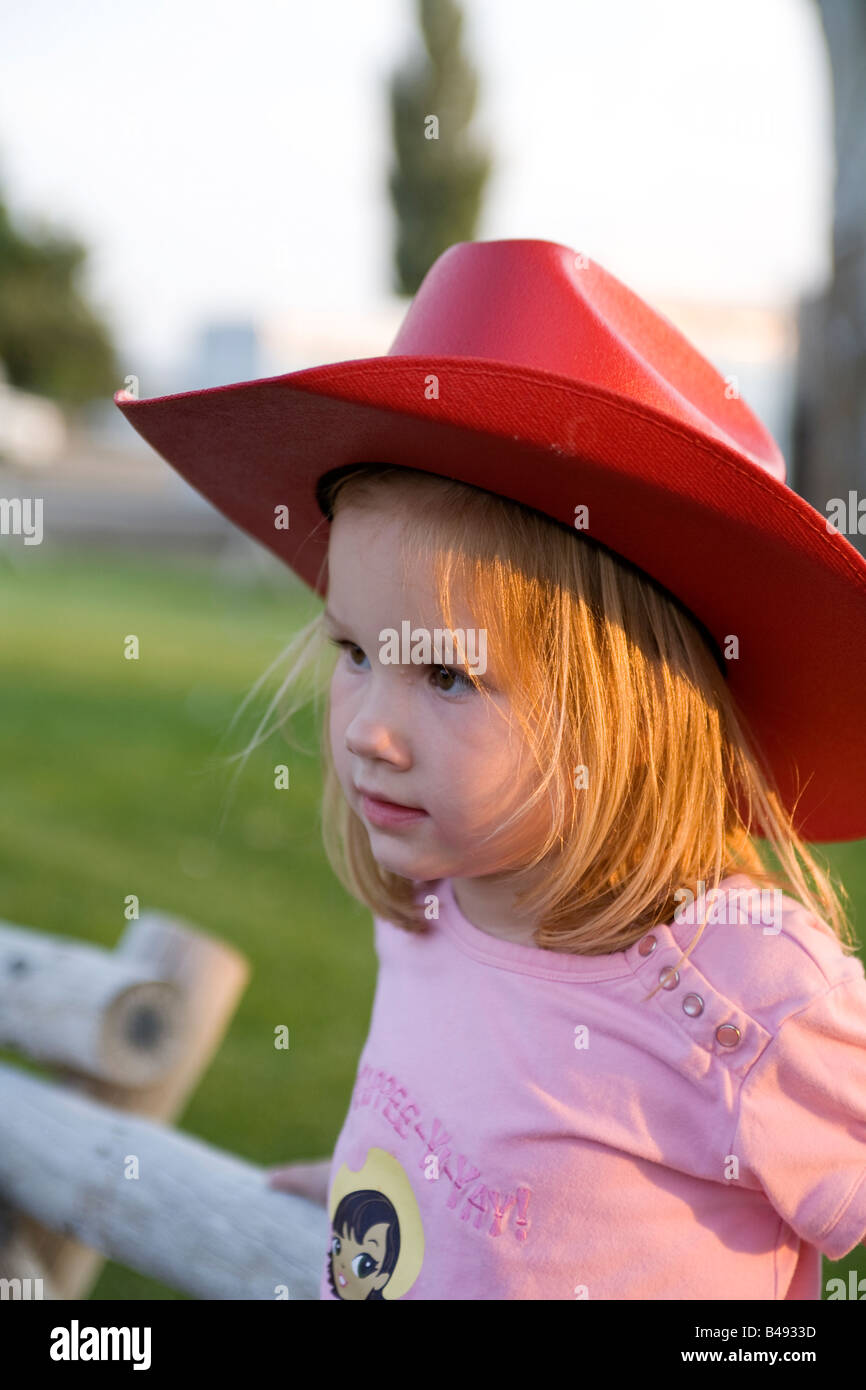 A young cowgirl with a large red coboy hat waits to enter the rodeo arena  Stock Photo
