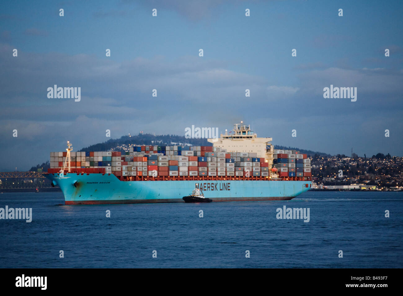 A tugboat assists a container ship change direction in Burrard Inlet Vancouver British Columbia Canada Stock Photo