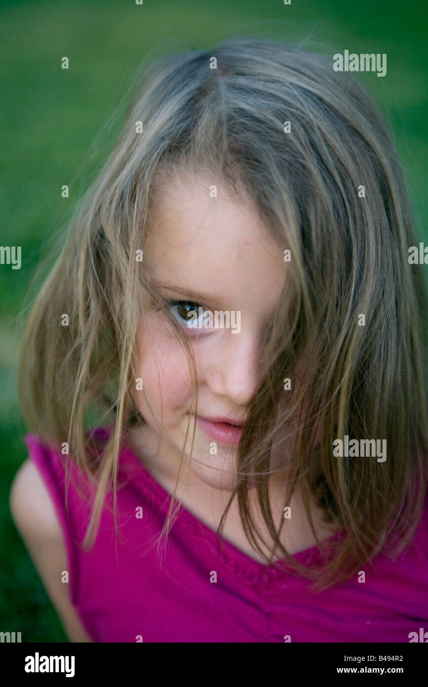 A girl with one eye covered by hair in a summer dress at the park at
