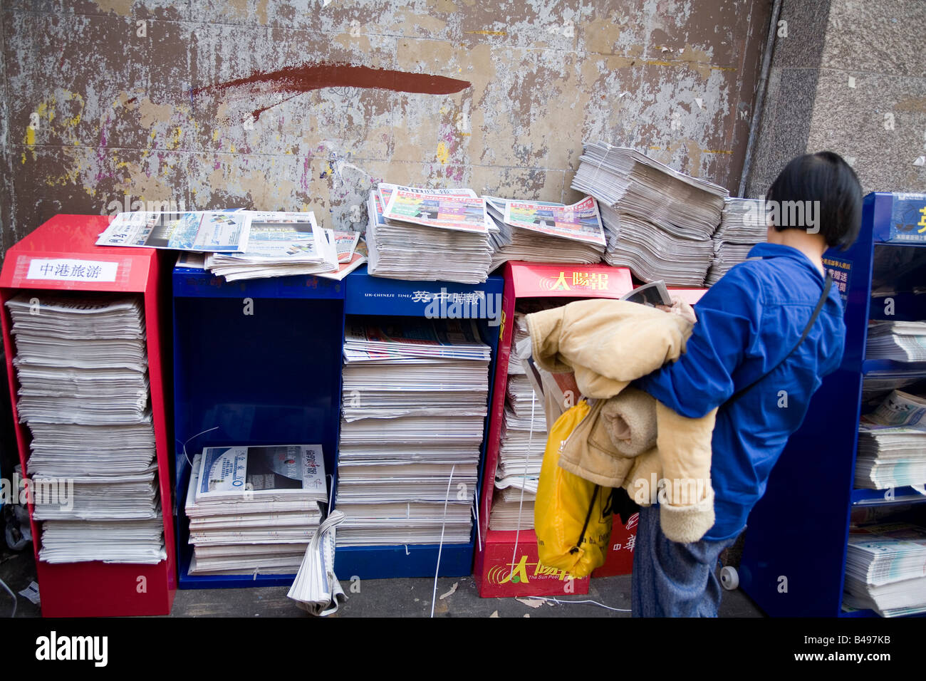 Woman picking free newspaper Chinatown Soho London Stock Photo