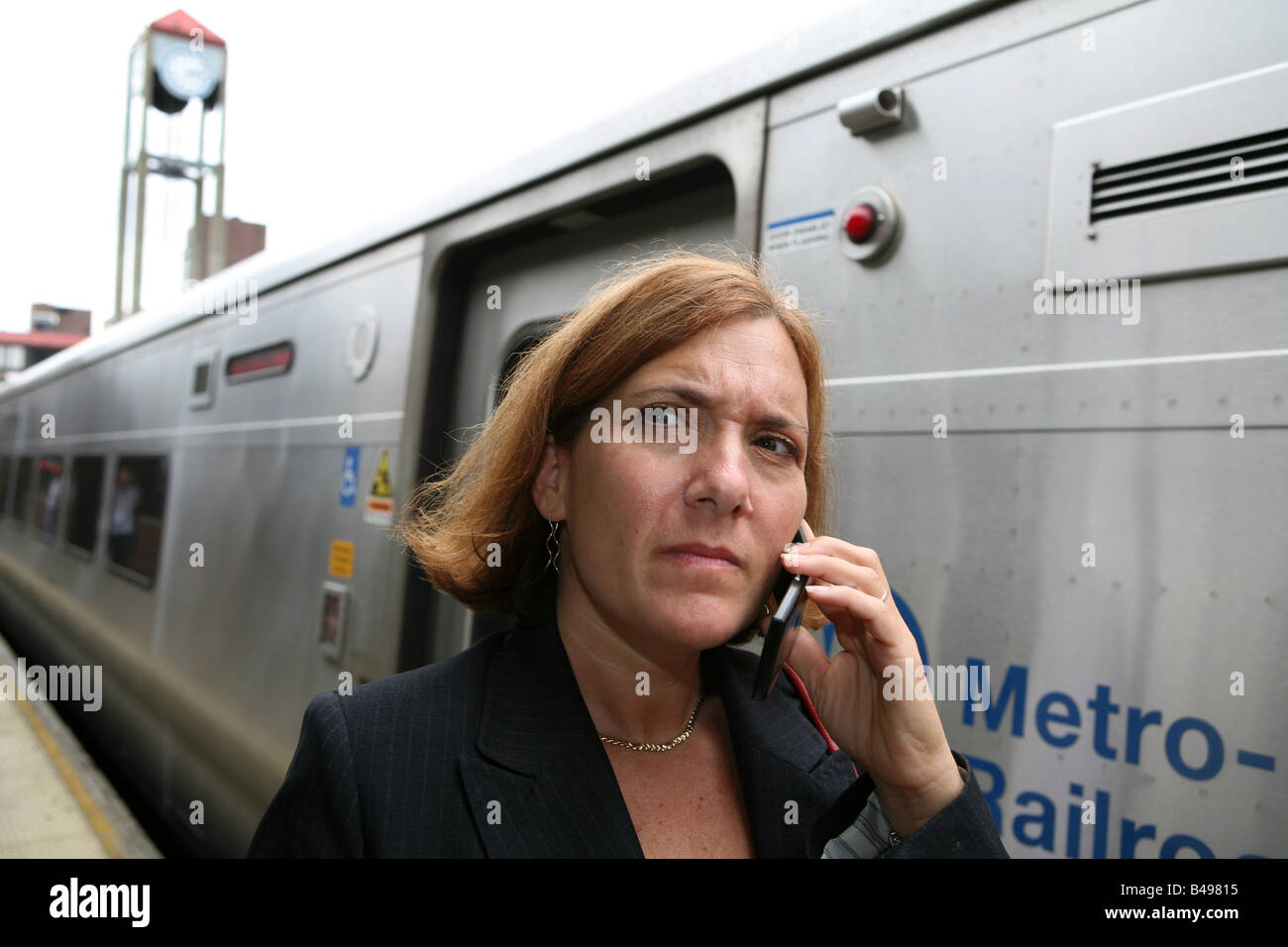 Commuting businesswoman keeps busy while awaiting the arrival of her train Stock Photo