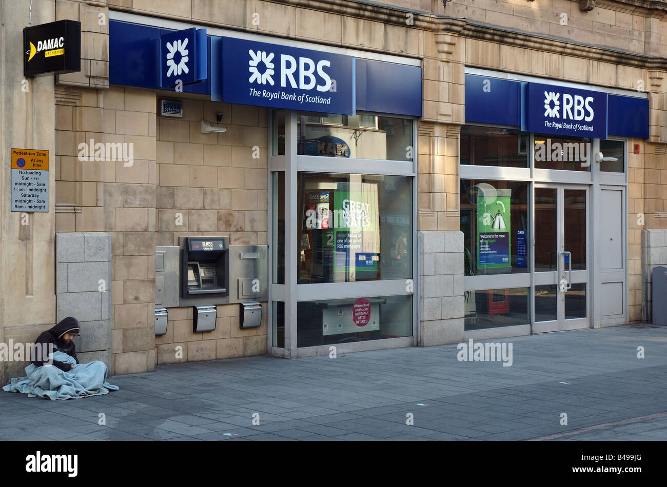 homeless person sitting beside a branch of the Royal Bank of Scotland, Leicester, England, Uk Stock Photo
