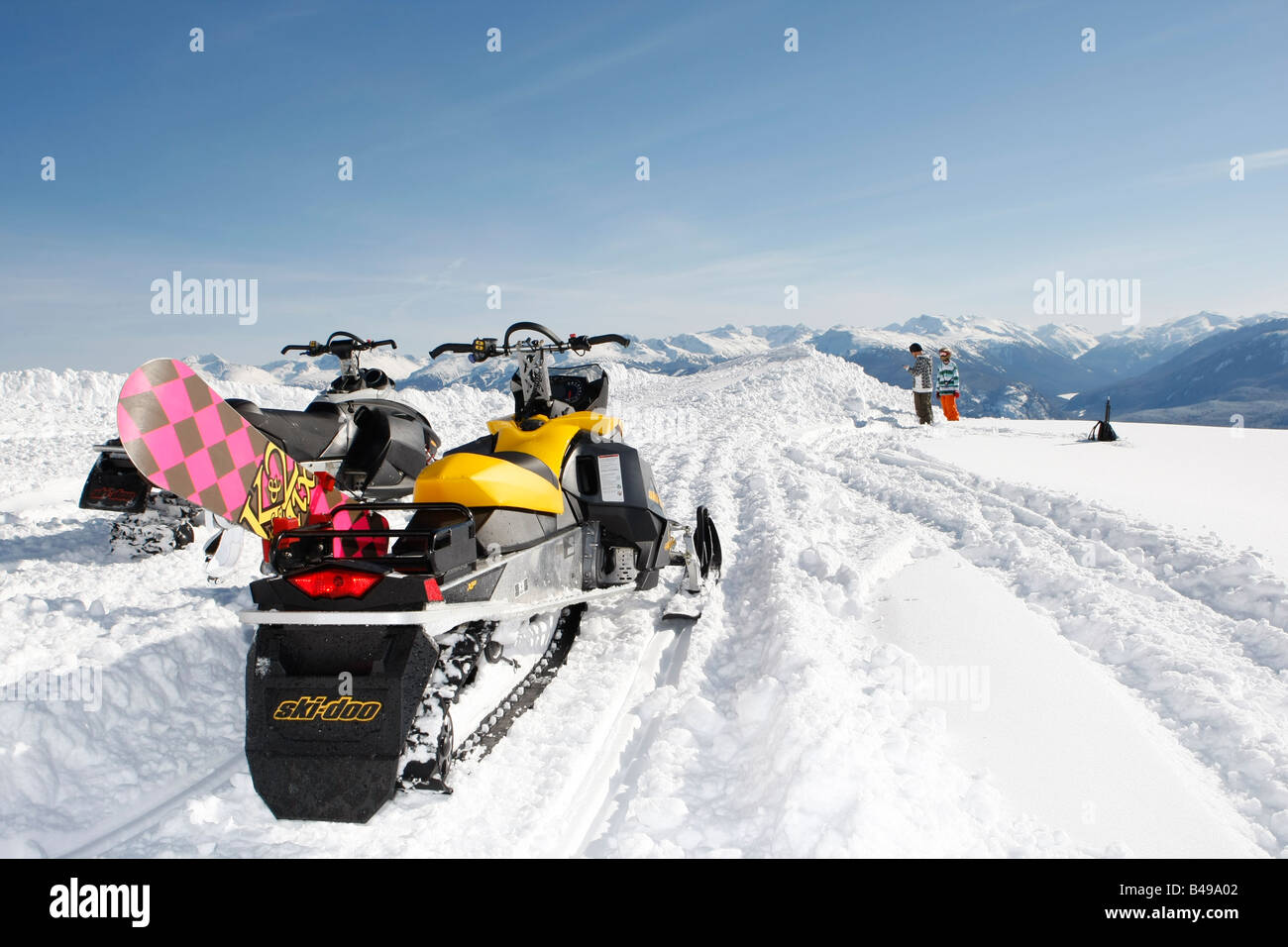 two snowmobiles with snowboards in the back country of Whistler BC Stock Photo