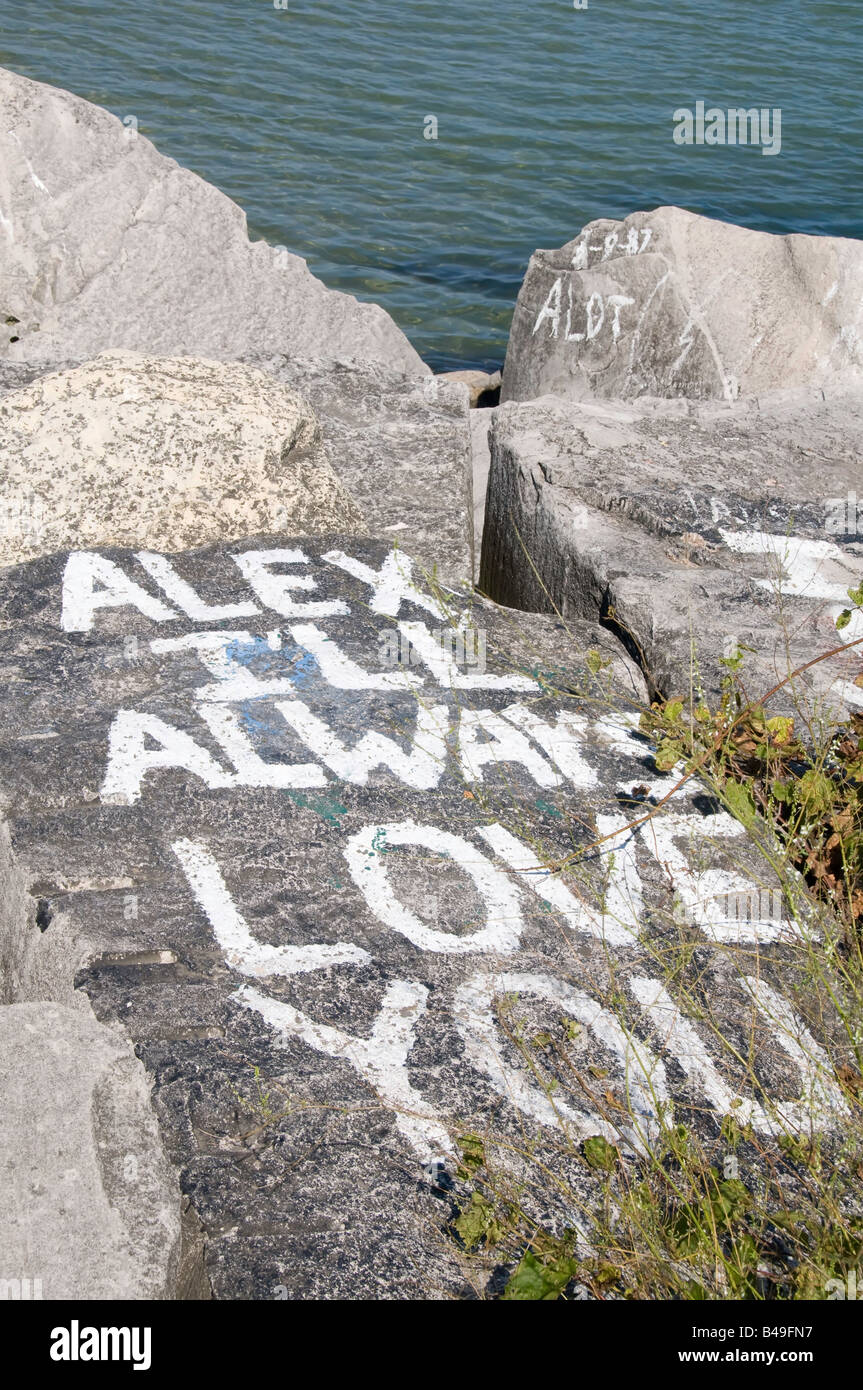 Lover's graffiti on rock by lake Stock Photo