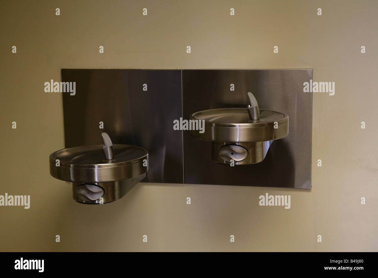 A wallmounted, stainless steel drinking fountain with two levels, a