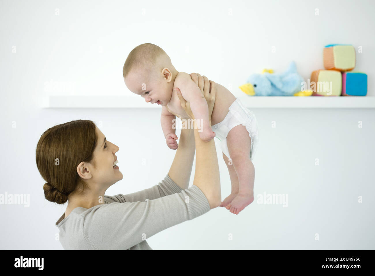 Mother lifting baby in the air, both smiling at each other Stock Photo