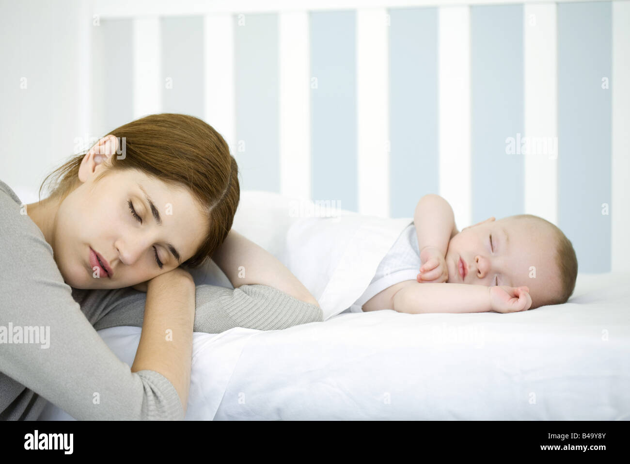 Mother resting head beside sleeping infant, eyes closed Stock Photo Alamy