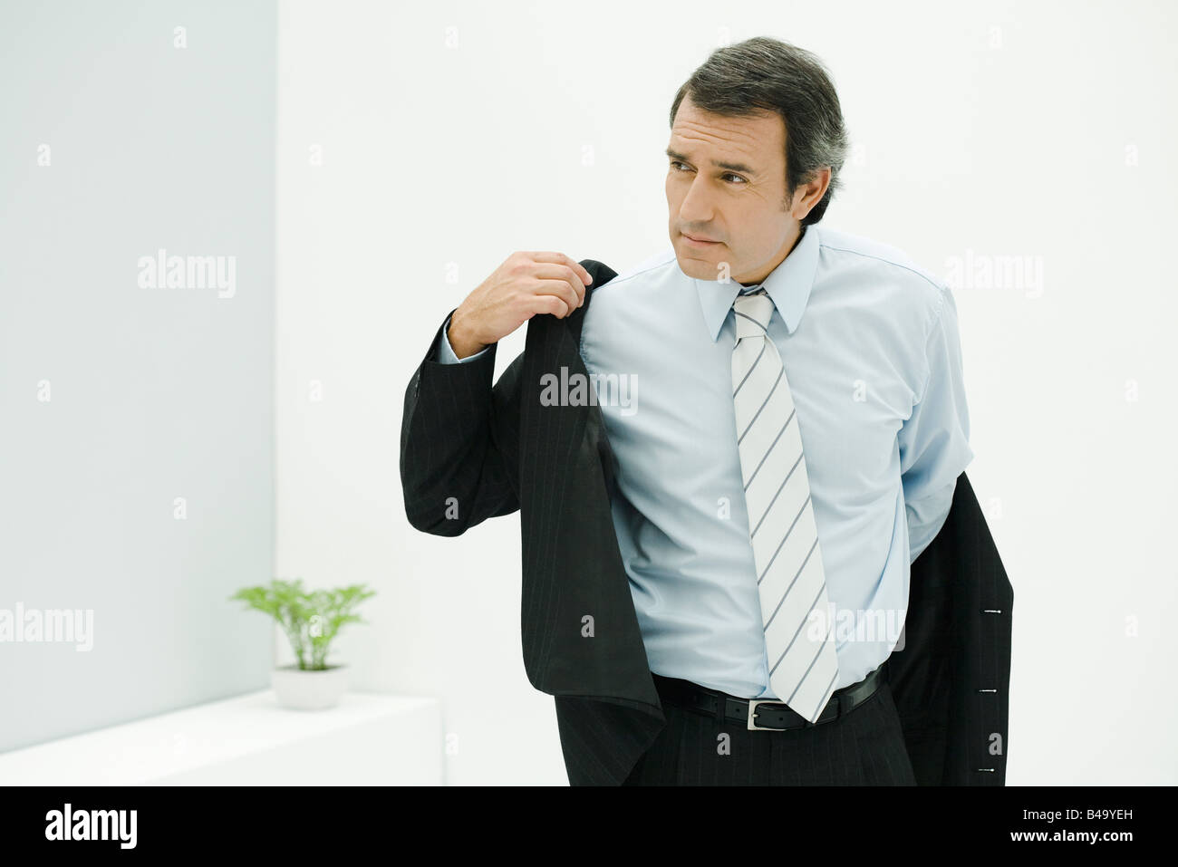 Man in suit putting on jacket, looking away Stock Photo