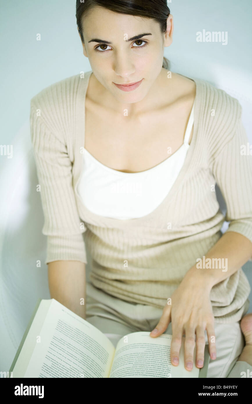 Woman holding open book, smiling at camera, high angle view Stock Photo