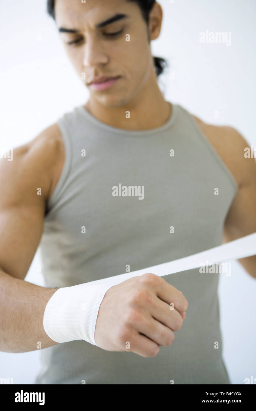 Man wrapping bandage around his wrist, looking down Stock Photo Alamy