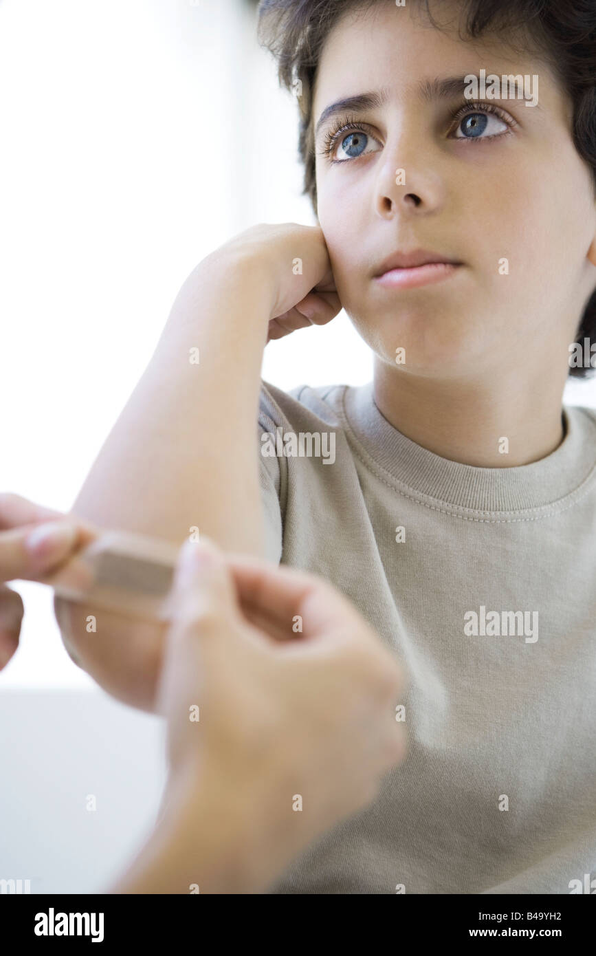 Boy having adhesive bandage applied to his elbow, cropped view Stock Photo