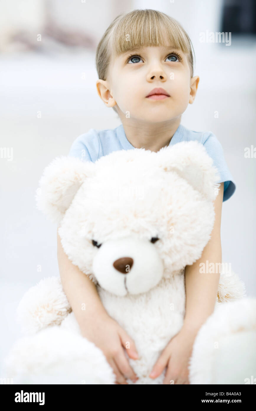 Little girl holding teddy bear, looking up Stock Photo - Alamy