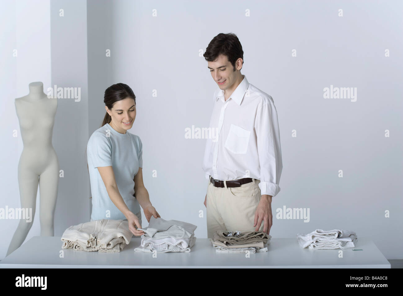 Saleswoman showing male customer a sweater, both smiling Stock Photo