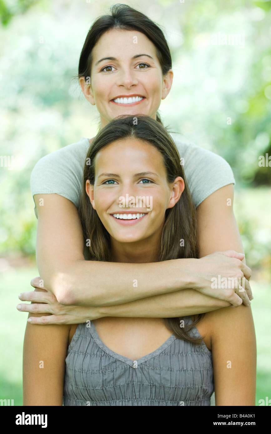 Mother Standing Behind Teenage Daughter Embracing Her Both Smiling At