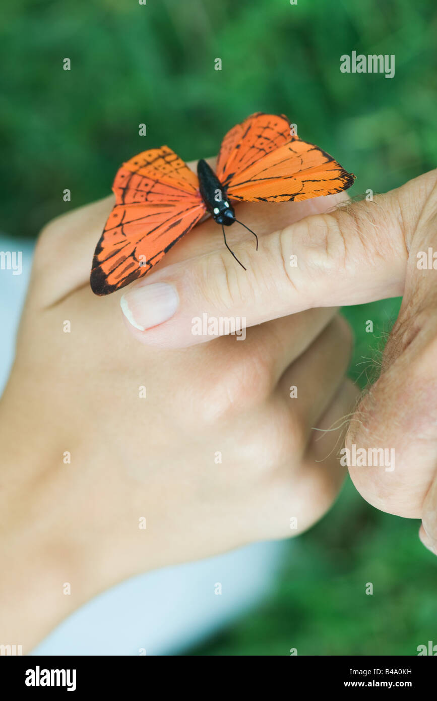 Young person with butterfly perched on hand, elderly person touching