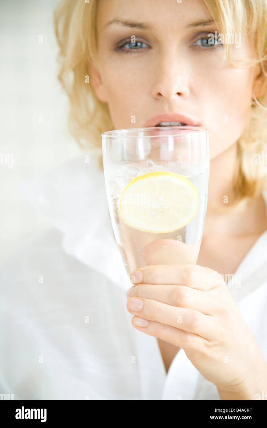 Woman holding up glass of water, looking at camera Stock Photo - Alamy