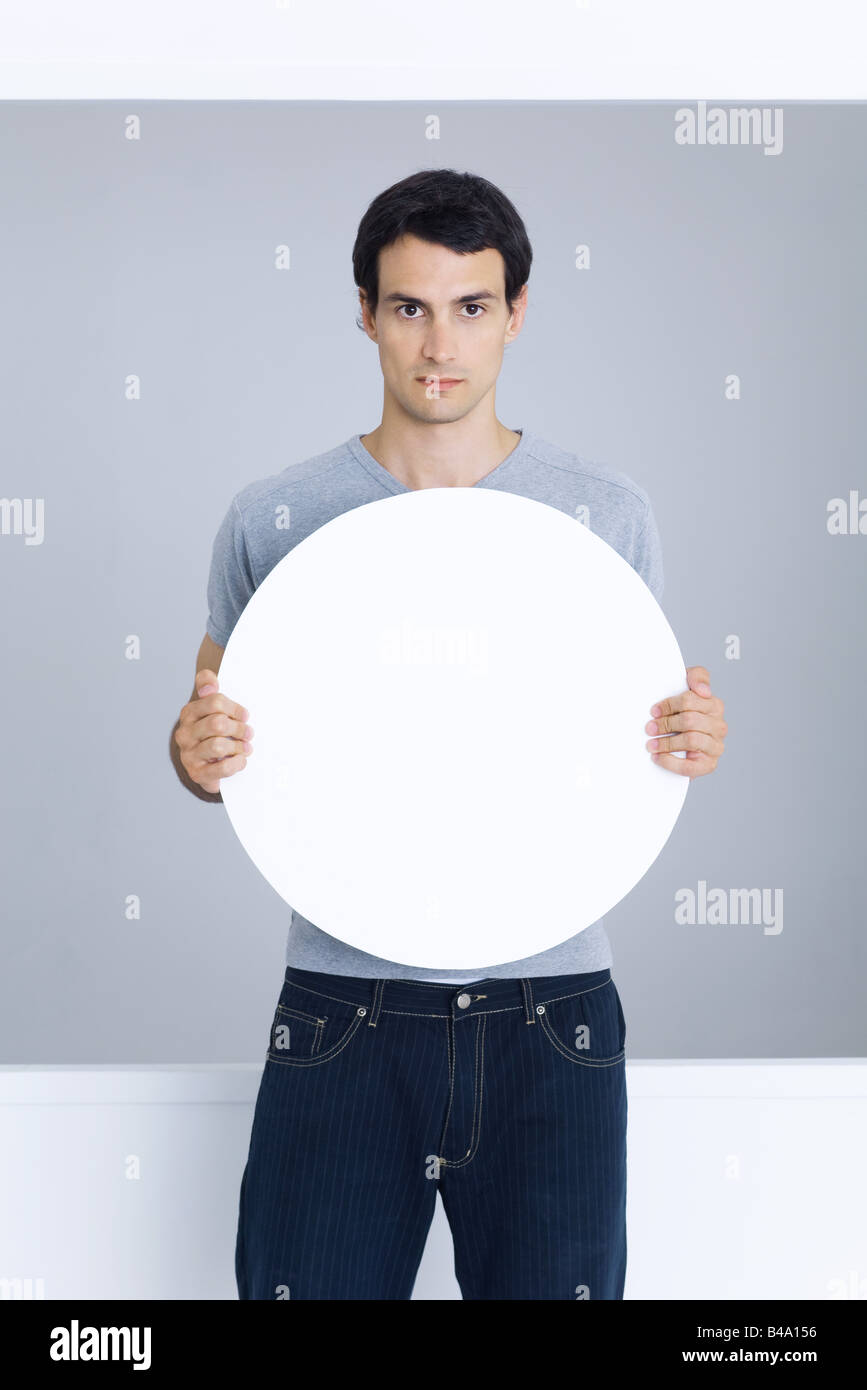 Man holding blank circular sign, looking at camera Stock Photo