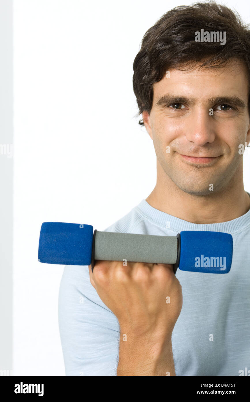 Man lifting dumbbell, smiling at camera Stock Photo