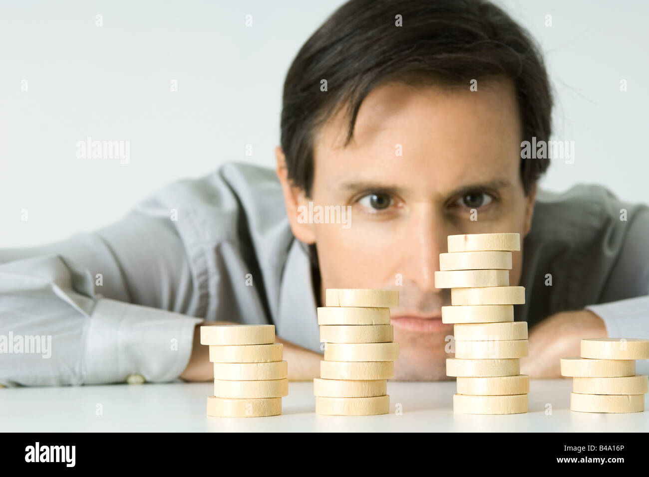 Man resting head on table, staring at stacked tokens Stock Photo