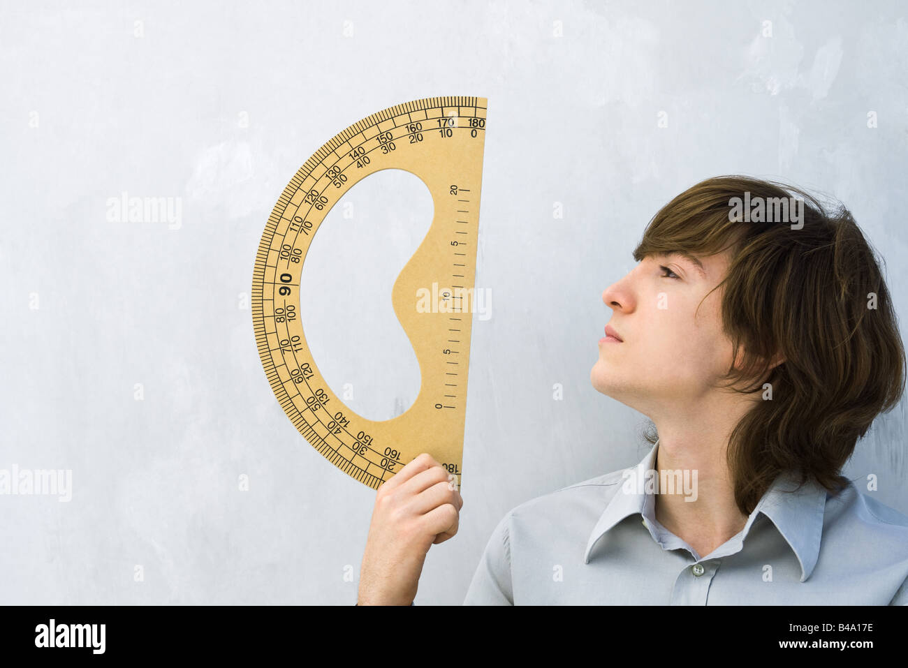 Young man holding up protractor, profile Stock Photo