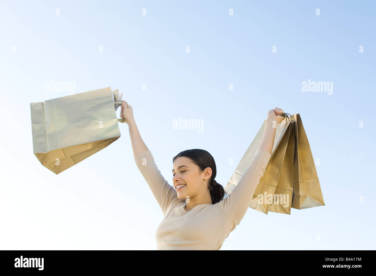 Woman holding up shopping bags, smiling, eyes closed Stock Photo