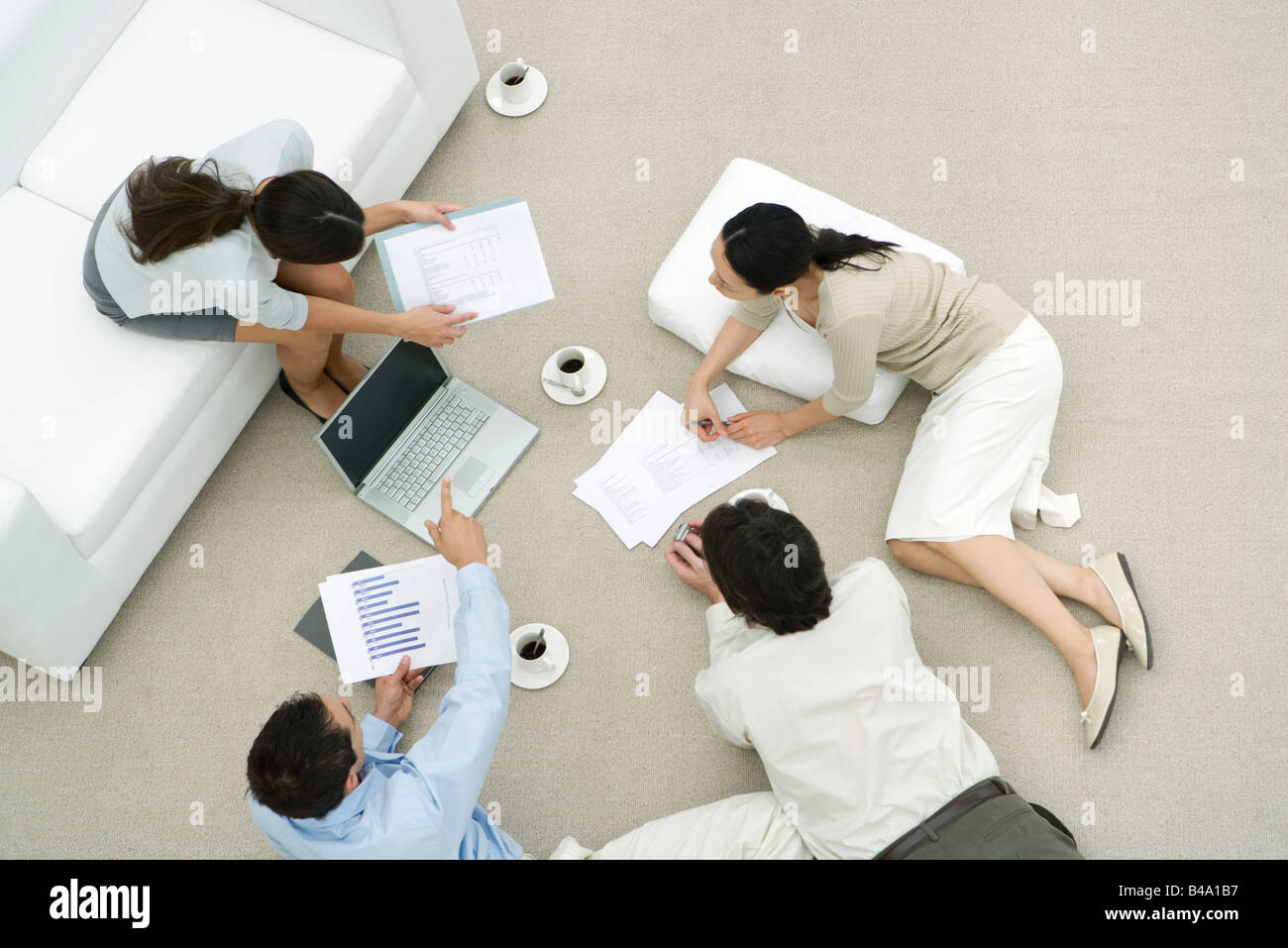 Team of professionals discussing documents in casual work environment, overhead view Stock Photo