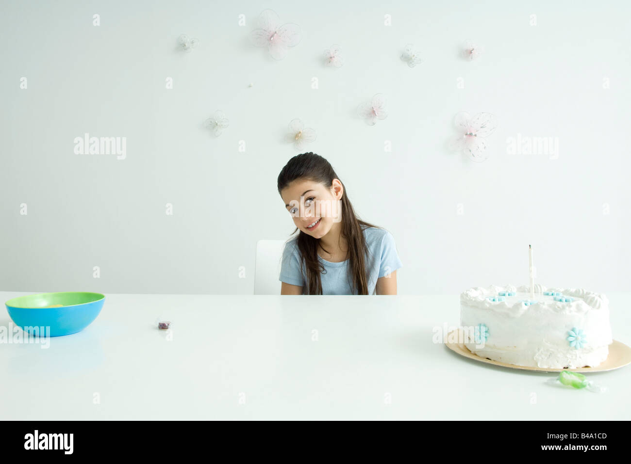 Girl sitting at table with birthday cake, smiling at camera Stock Photo ...