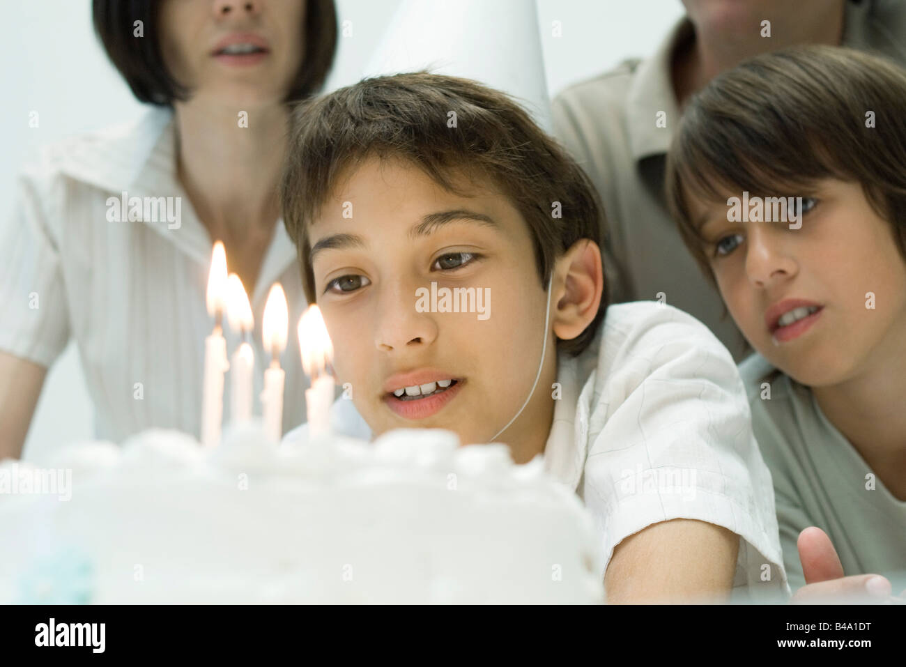 Boy making a wish before blowing out candles on birthday cake Stock
