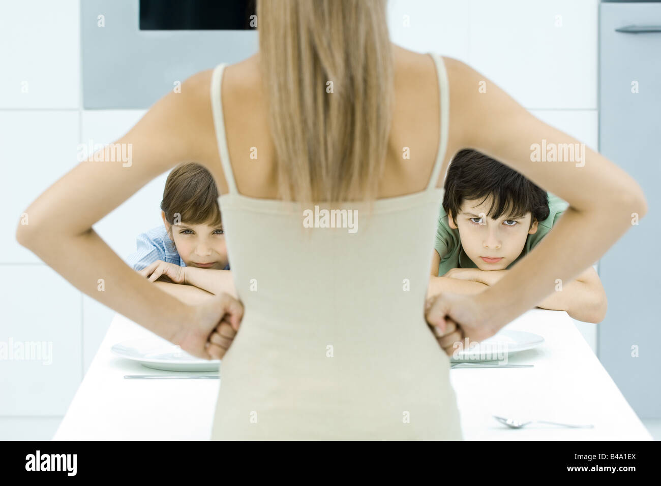 Mother standing with hands on hips in front of two sulking boys, cropped view Stock Photo