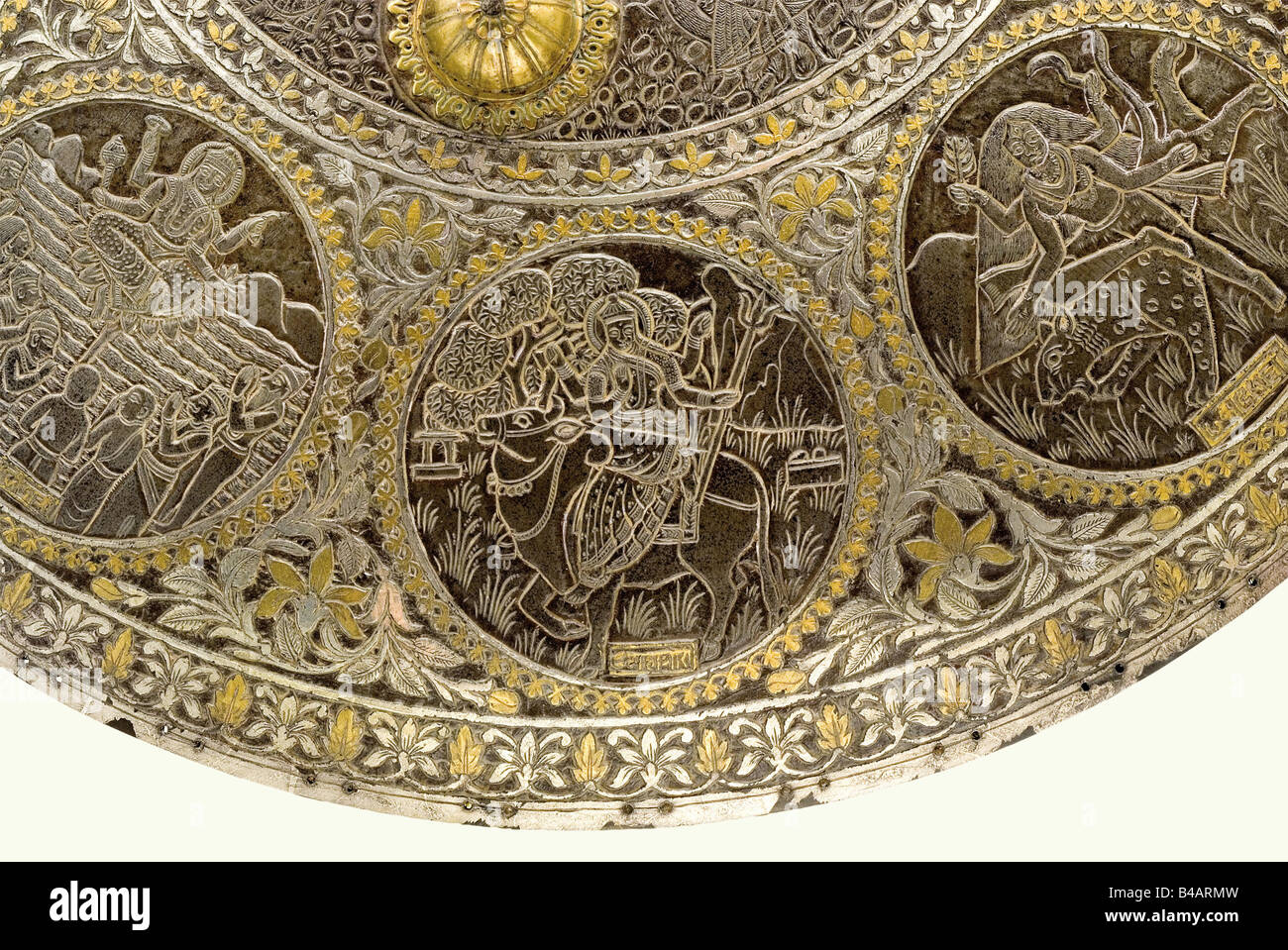 A splendid chiselled Indian shield, Jaipur, end of the 19th century. A slightly cambered shield. The entire surface is cut steel with rich gold and silver inlay. The centre bears the coat of arms of the Maharaja of Jaipur with the God Vishnu in a Sun Burst. There are four additional gods between the flower-shaped brass umbos, with a succession of nine surrounding circular cartouches bearing Hindi inscriptions. The surface is sealed with clear lacquer. On the back are four suspension rings with straps, a fist cushion (damaged), and brocaded lining sewnto the rim, Stock Photo