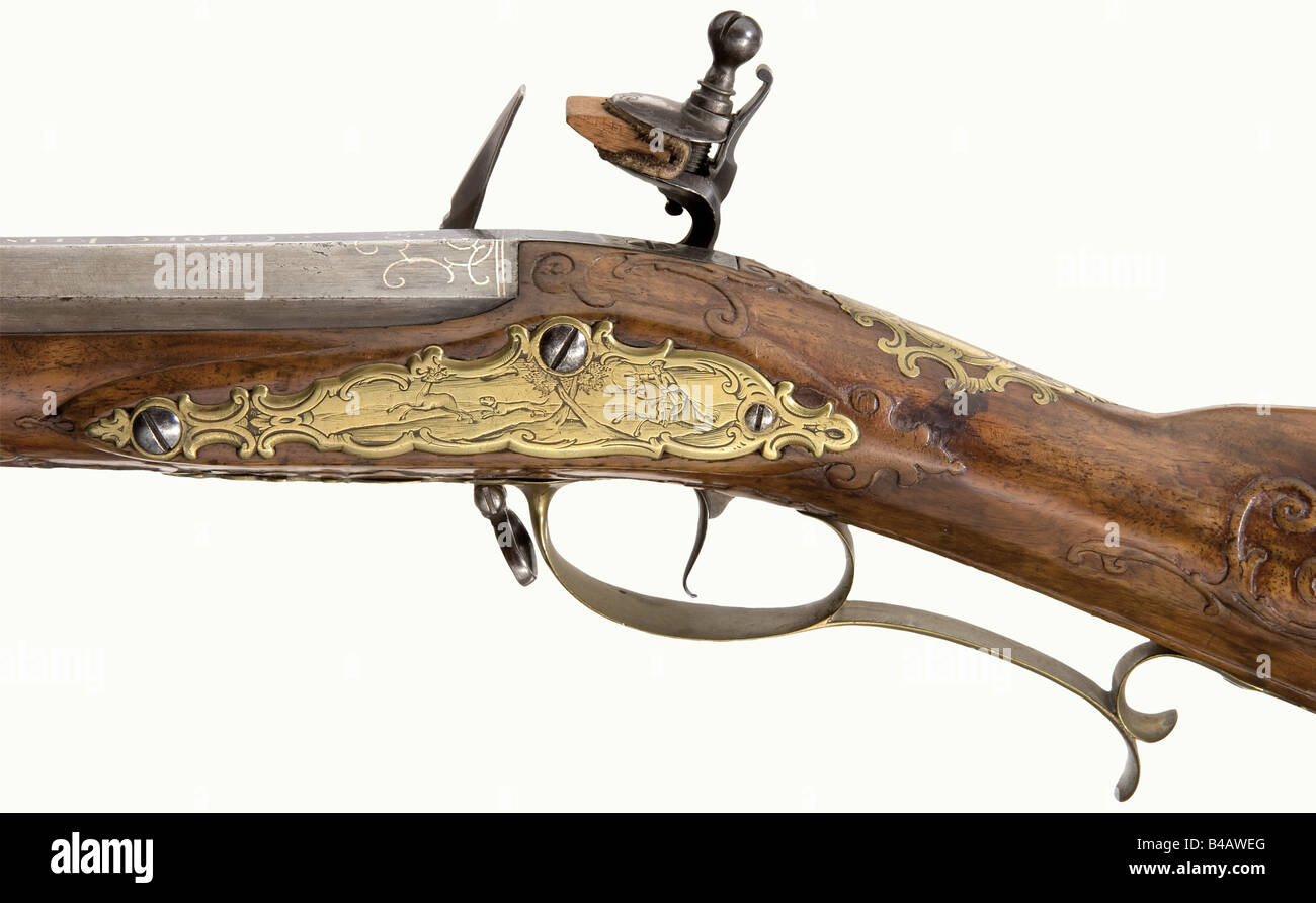 A flintlock rifle, Georg Keiser in Vienna, circa 1730. Heavy octagonal barrel with a slightly reduced diameter in the middle. Seven groove rifled bore in 17 mm calibre. Engraved dovetailed folding sights. Silver inlaid decorative scrolls on the breech and the base of the barrel with the signature 'Georg Keiser in Wienn'. Tang engraved with the number '1'. The lock bears finely engraved rocaille decoration. The action block cover is a replacement. Gold bushed vent. Beautifully figured, lightly carved walnut full stock. Small repair on the forearm. Patchbox. Fine, Stock Photo