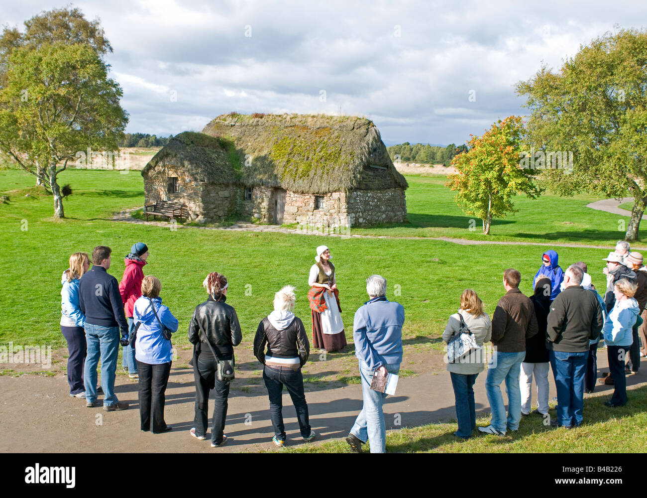 Tour group at the old Leanach Farmhouse being guided round the Historic Culloden Battlefield site Stock Photo