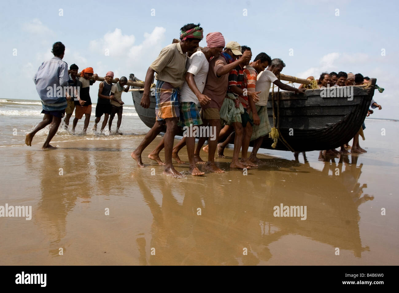Fishermen carring their boats from sea to the beach after their fishing activities in Digha, West Bengal,India Stock Photo