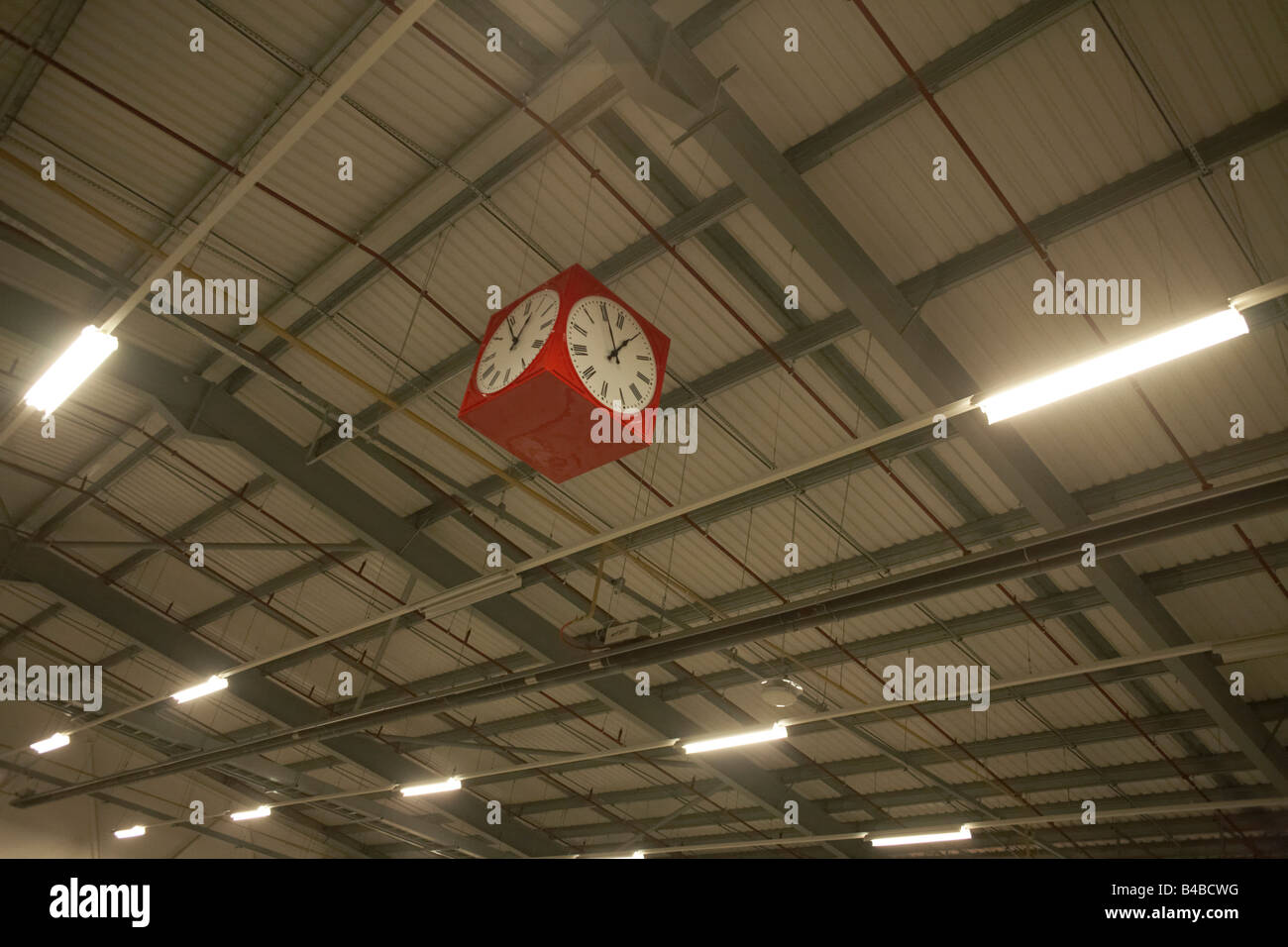 Red clock hangs from warehouse roof of cross-docking area of of Royal Mail's DIRFT logistics park in Daventry Stock Photo