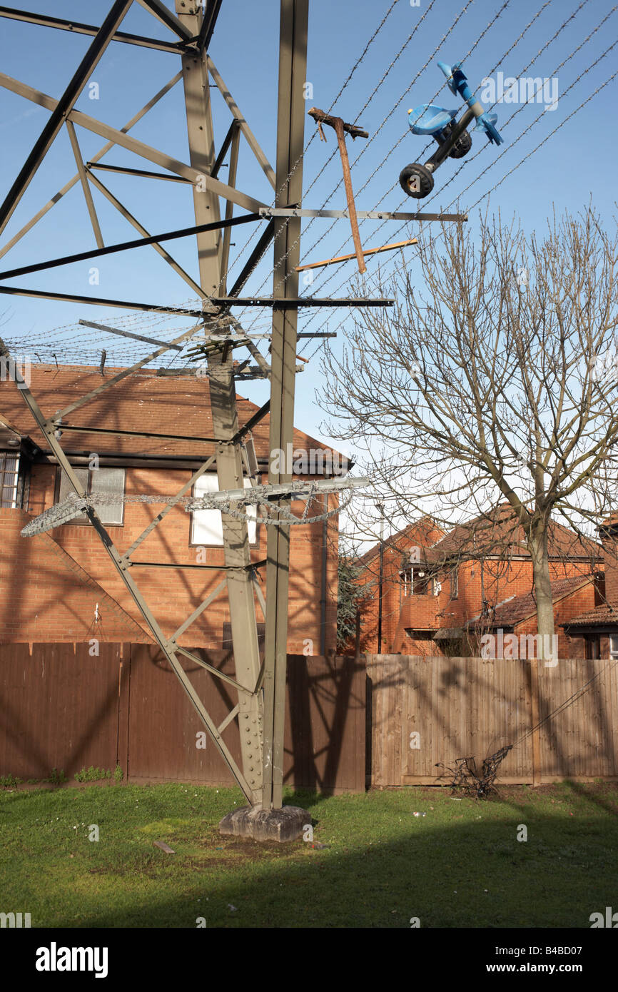 Steel girders of an electricity pylon with trapped tricycle stands close between housing on an estate in Beckton, East London Stock Photo