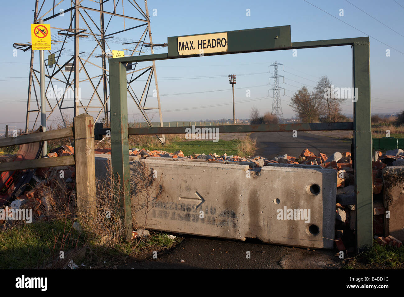 To deter fly-tippers, a barricaded and disused car park entrance is near L6 electricity pylons at Dartford, Kent. Stock Photo