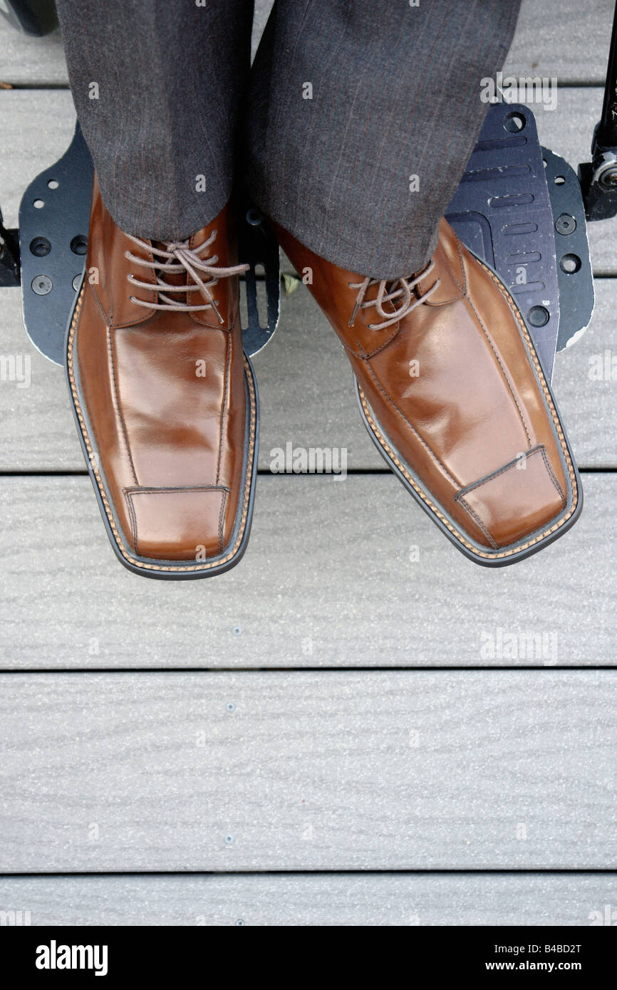 Detailed Portrait of the Feet of a Man in a Wheelchair He is wearing Brown Shoes and his feet are on the Foot Rests Copy Space Stock Photo