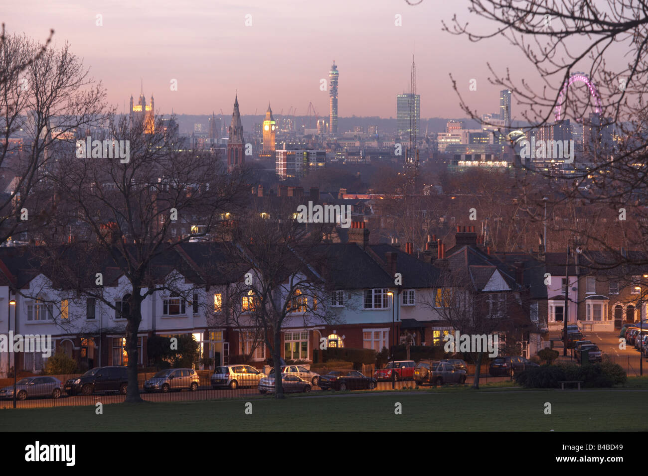 Early evening lights glow from windows of Edwardian era semi-detached houses and 100 year-old ash trees and Westminster behind. Stock Photo