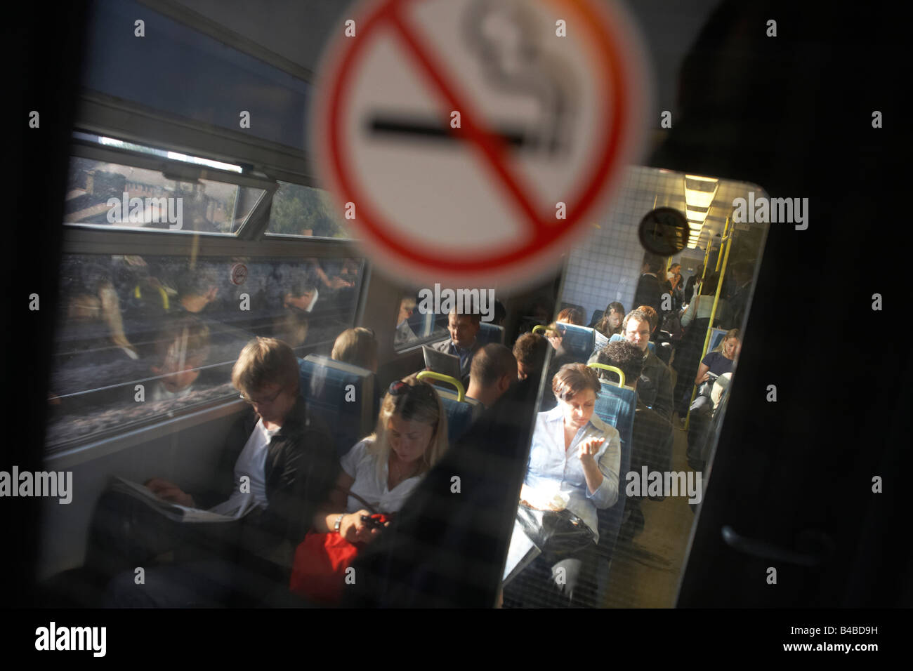 Commuters and No Smoking sign on a railway train carriage travelling into London between Victoria and London Bridge stations Stock Photo