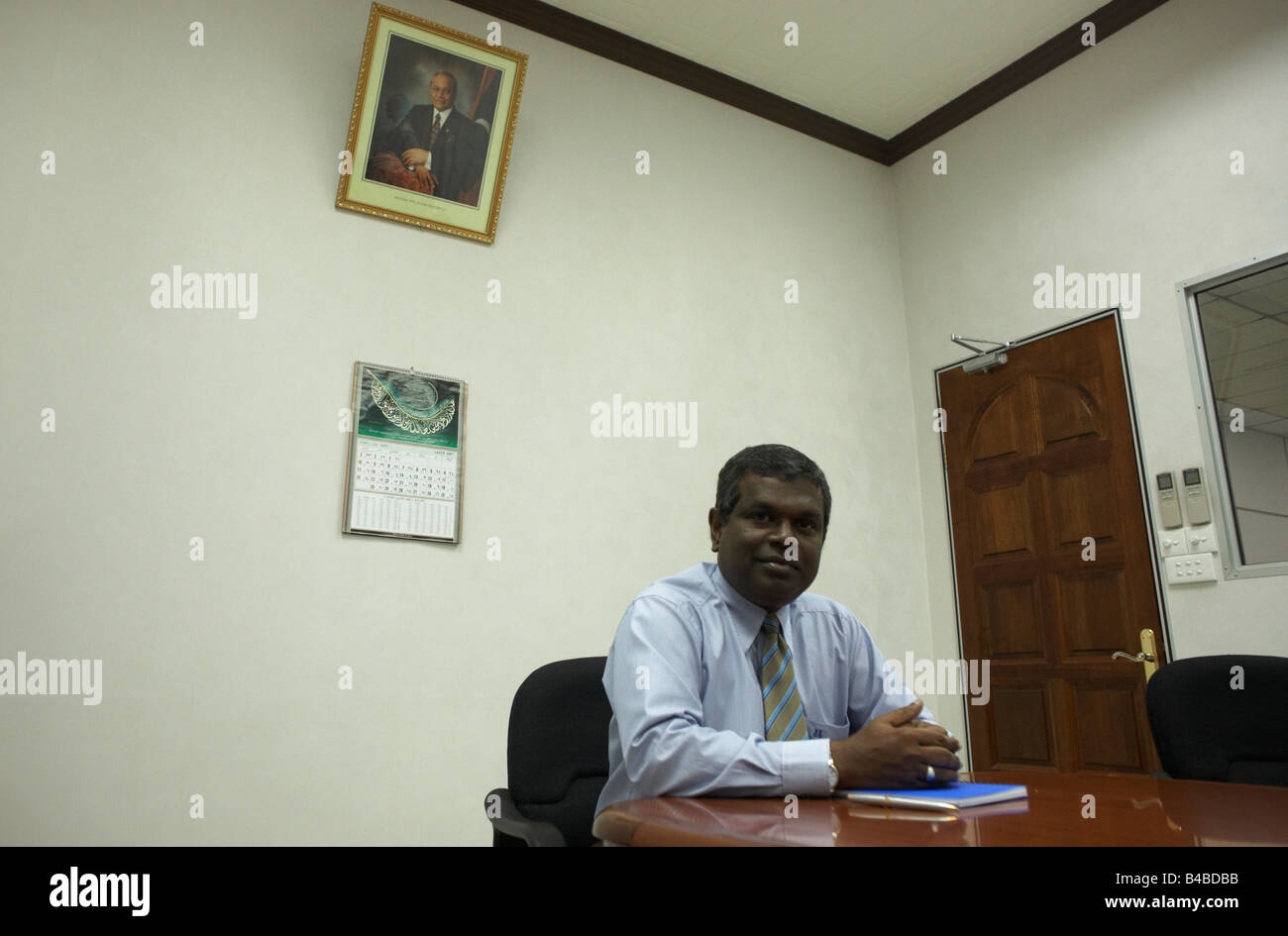 Under a portrait of ex-President Gayoom is Mr Abdullah Naseer at his desk in the Fisheries Ministry, Republic of the Maldives Stock Photo