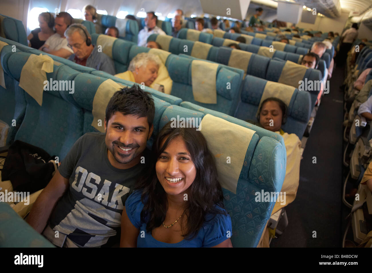 Honeymoon couple on their return home after a holiday in the Maldives return home in economy class grinning Stock Photo