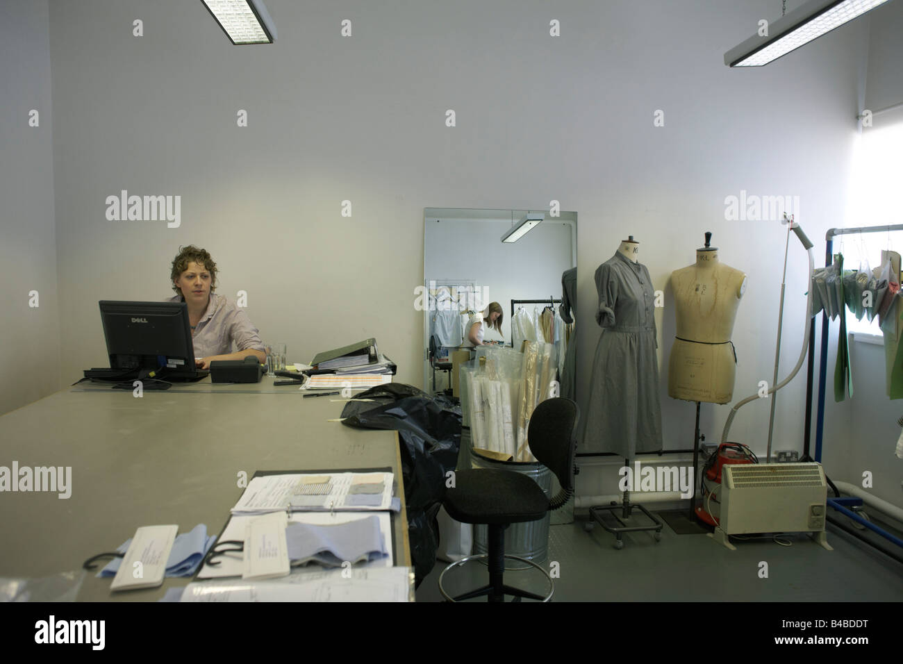 A garment tailor works with mannequins in the design studio at